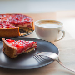 Still life with a Cup of coffee and sweet dessert with strawberries, cheesecake cake with slices of berries in jelly on top.