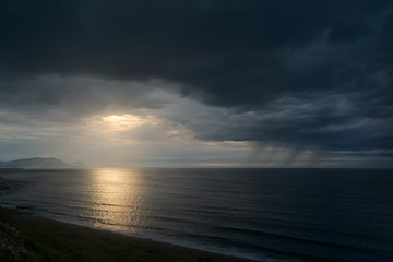 dark seascape with stormy clouds and rain at sunset - Powered by Adobe