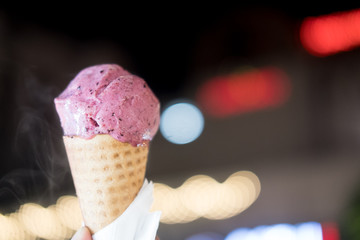 Blueberry ice cream in waffle cone on young man hand