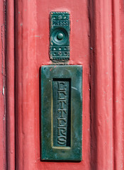 Close up on vintage letterbox and doorbell on painted wooden door