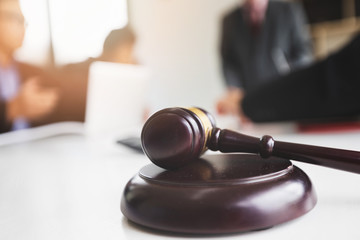 Wooden gavel on table in lawyer's office. Lawyer having team meeting with the client. Concepts of law, advice, legal services.