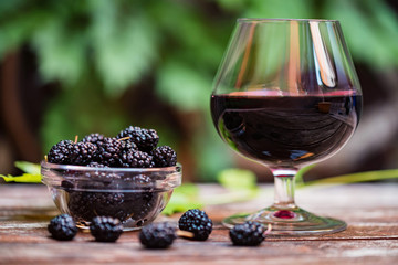 Close up fresh mulberries fruit in bowl and wine in glass