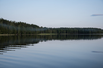 Panorama of the lake shore at sunset with reflection in the water. Finland .