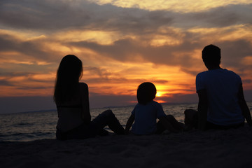 Silhouette of family watching sunset at beach. Happy family enjoy on sea on summer vacation