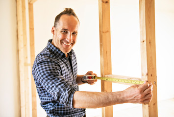 A man worker in the carpenter workroom renovation using tape