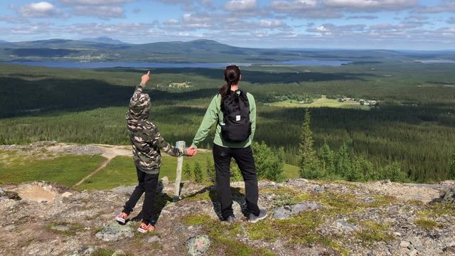 A mother and her son admiring the view while trekking in the swedish mountains