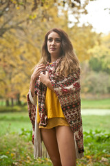 Happy Portrait fashion of a beautiful young Caucasian woman with a scarf,long legs  and yellow pullover in autumn park,red green yellow threes. Autumn, season and people concept.Autumn lifestyle