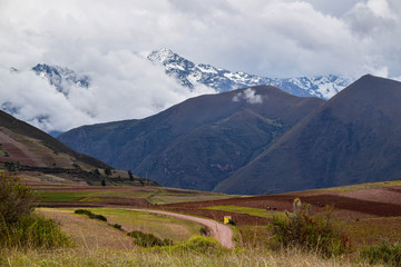 Fototapeta premium Empty road going through the farm lands in Sacred Valley in Peru with the mountains in the background