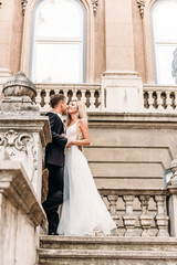 Bride and groom hugging in the old town street. Wedding couple in love. Luxury rhinestone dress. Hot summer days.