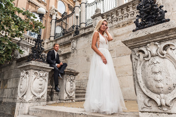 Bride and groom hugging in the old town street. Wedding couple in love. Luxury rhinestone dress. Hot summer days.