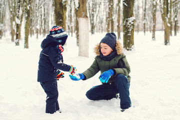 Fototapeta na wymiar Happy children playing on snow in winter time. Winter leisure with children in cold snowy days. Happy siblings having fun with snow. Christmas holidays
