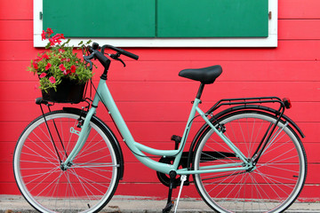Fototapeta na wymiar aquamarine bike in front a red wooden house