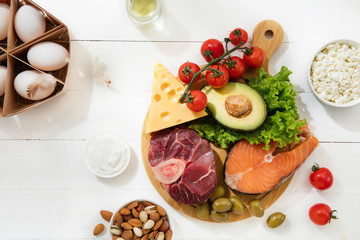 Ketogenic low carbs diet - food selection on white wooden background. Balanced healthy organic ingredients of high content of fats. Nutrition for the heart and blood vessels. Meat, fish and vegetables