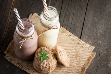 Photo of fresh Made Chocolate Banana Smoothie on a wooden table with cookies, banana and coconut. Milkshake. Protein diet. Healthy food concept.