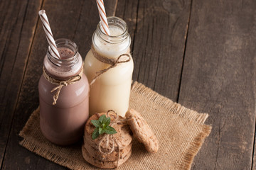 Photo of fresh Made Chocolate Banana Smoothie on a wooden table with cookies, banana and coconut. Milkshake. Protein diet. Healthy food concept.