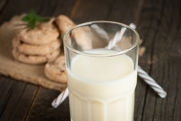 Photo of fresh Made Chocolate Banana Smoothie on a wooden table with cookies, banana and coconut. Milkshake. Protein diet. Healthy food concept.