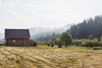 Wooden house on a background of morning fog in the mountains.
