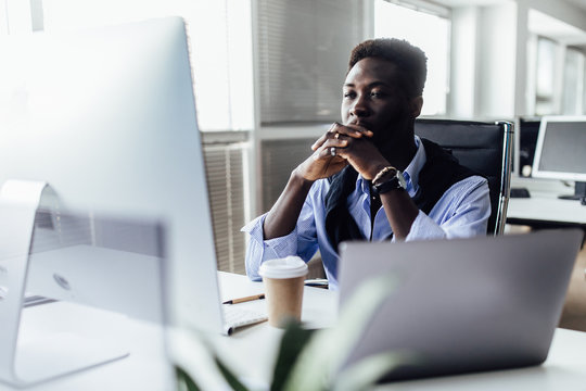 Tensioned or surprised man is sitting in office. Serious and concentrated male in suit is working at notebook and looking resent and worried.