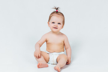 Infant child baby girl in diaper lying sitting happy smiling on a white background. Lifestyle.
