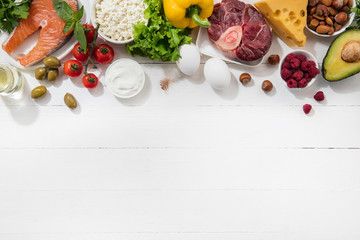 Ketogenic low carbs diet - food selection on white background. Balanced healthy organic ingredients of high content of fats for the heart and blood vessels. Meat, fish and vegetables. Copyspace.