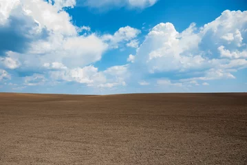 Zelfklevend Fotobehang Empty brown soil of field and blue sky for natural background © Yakov