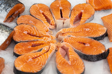 Fresh salmon meat slices on ice in a market window. Texture or background, selective focus.