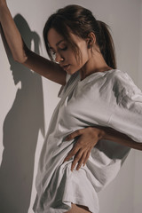 Beautiful young seductive woman posing in room on white background. Fashion glamour sexy girl model in shirt and lingerie. Stylish beauty portrait