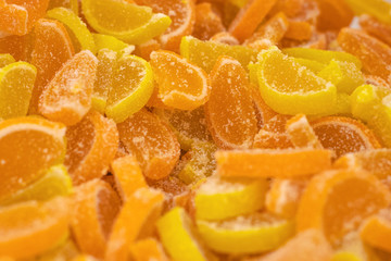 Marmalade in the form of slices of lemon and orange, sprinkled with sugar, close-up. Background of colorful sweets, selective focus.