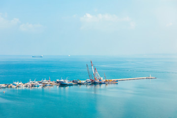 Fototapeta na wymiar Industrial port or harbor with container or cargo ships and cranes in iskenderun seaport at Hatay city of Turkey. Transportation and logistic at Mediterranean sea. 