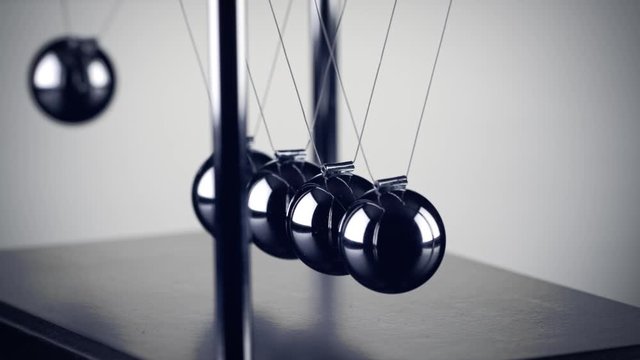 The chrome balls of a Newton&rsquo;s Cradle colliding in slow motion