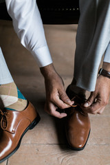 man tying his brown leather shoes, groom getting ready for wedding, business man