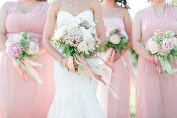 bride and bridesmaids holding wedding bouquets, pink dresses