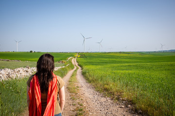 Woman looking out over panoramic view of Apulian countryside with wind farm. Puglia region, Italy.