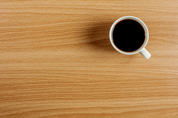 white ceramic coffee cup on wooden desk. - blank space for advertising text.