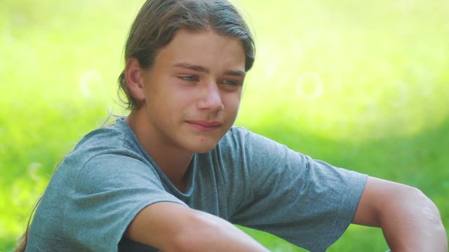 Portrait of a teenager meditating in nature. Boy meditates thinks outdoors. 