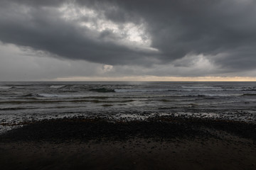 Black sand beach with green vegetation in a stormy day in Bali, Indonesia