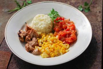 rice, vegetables and meat (corn, tomato salsa, greens, vegetables) portion serving. top food background. copy space