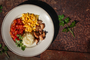 rice, vegetables and meat (corn, tomato salsa, greens, vegetables) portion serving. top food background. copy space