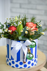 Bouquet of Christmas tree with Christmas decorations and live roses. On a light background in a striped box.