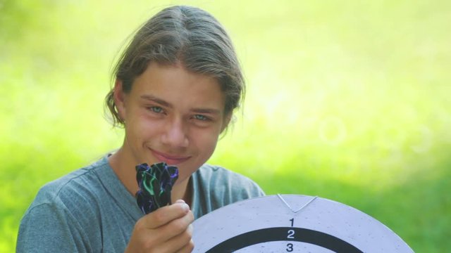 Portrait of a teenager boy playing darts. A boy plays an outdoor darts game.