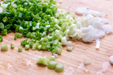 chopped  fresh green onions on a rustic wooden board with drops of water. Close-up. cooking greens for the dish
