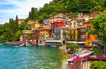 Varenna, Italy. Picturesque town at lake Como. Colourful motley Mediterranean houses on knoll by coastline among green trees. Popular health resort and touristic destination location. Summer day.