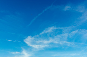 Schöner Blauer Himmel mit Mond und interessanten weißen, feinen, durchscheinenden und faserigen Schleierwolken aus Eiskristallen bei Sonnenschein am Morgen