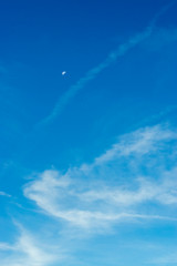 Schöner Blauer Himmel mit Mond und interessanten weißen, feinen, durchscheinenden und faserigen Schleierwolken aus Eiskristallen bei Sonnenschein am Morgen