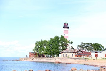 red-and-white lighthouse on the beach rocks in the water in the foreground