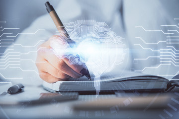 Double exposure of woman's writing hand on background with brain hologram. Concept of brainstorming.
