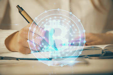 Cryptocurrency hologram over woman's hands writing background. Concept of blockchain. Double...