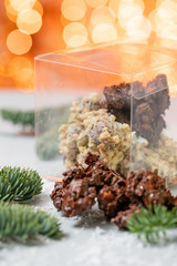 Rocks with chocolate and nuts. Christmas theme. Healthy sweet dessert snack. Granola bar with nuts, fruit, chocolate and berries. Garland lamps bokeh on background. Copy space