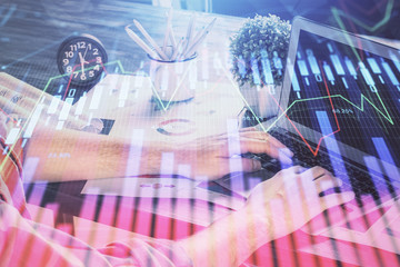 Double exposure of stock graph with businessman typing on computer in office on background. Concept of hard work.