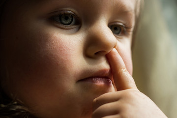 Toddler child picks her nose close portrait